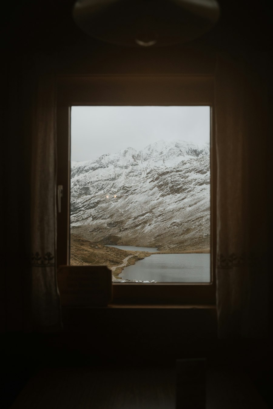 Snowy mountains seen through a dark window