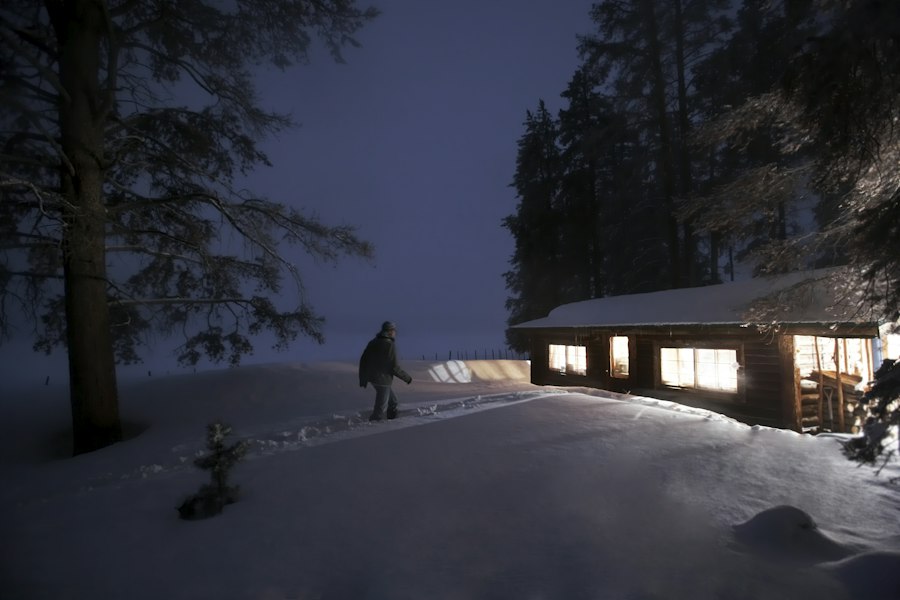 Cabin with lit windows in the snow at blue hour