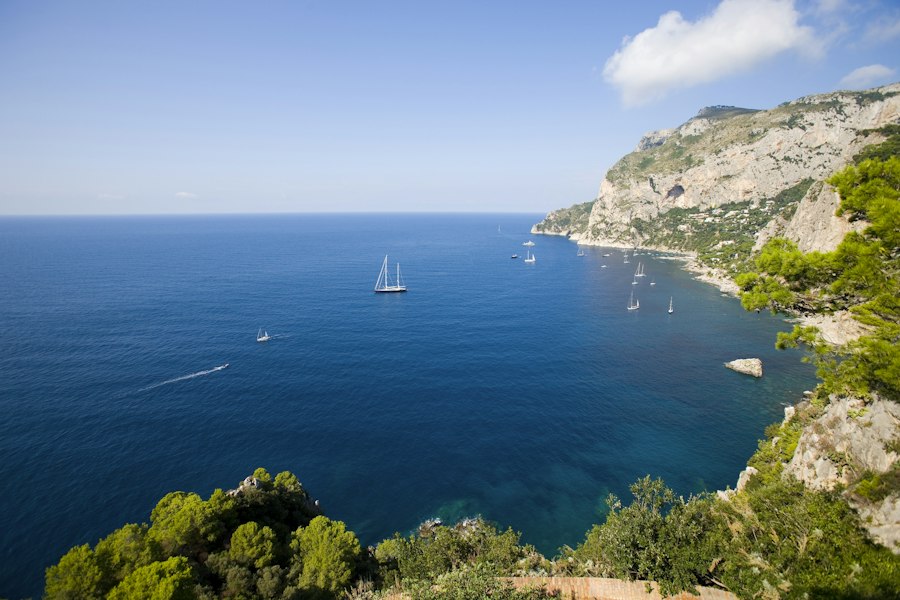 The sea seen from a cliff with boats far below